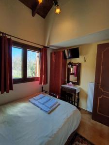 ein Schlafzimmer mit Bett, Fenster und Schreibtisch in der Unterkunft Optasia in Karpenisi