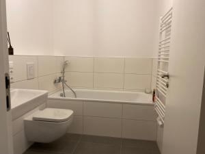 a white bathroom with a toilet and a bath tub at Berlin in Niederdorla