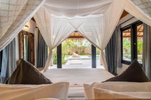 a bedroom with a bed with mosquito nets at Breathe Villa Meno in Gili Meno +69 photos