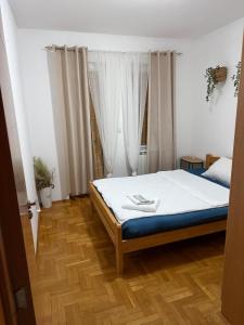 a bedroom with a bed with white sheets and wooden floors at Barbello in Stara Pazova