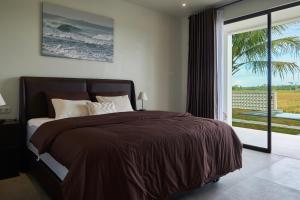 ein Schlafzimmer mit einem großen Bett und einem großen Fenster in der Unterkunft Leafy's Lodge in Padangnegeri