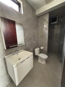 ein Badezimmer mit einem weißen Waschbecken und einer Toilette in der Unterkunft Leafy's Lodge in Padangnegeri