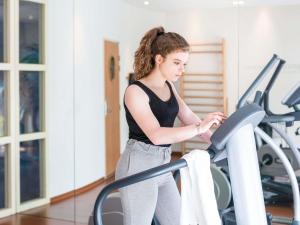 a woman on a treadmill in a gym at Novotel Suites Reims Centre in Reims +49 photos