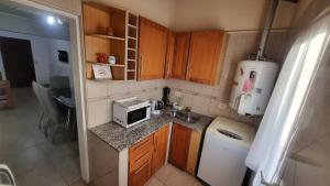 a small kitchen with a sink and a microwave at Hospedaje "LUZ" in Olavarría