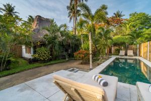 a backyard with a swimming pool and a house at Breathe Villa Meno in Gili Meno