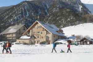 a group of people walking in the snow in front of a building at 10214 Chalet d'exception nature sport et bien être sauna,jacuzzi hammam frigidarium in Cervières