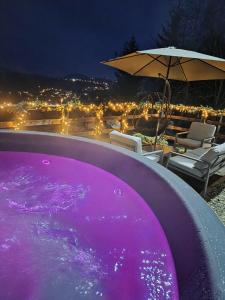 a purple swimming pool with an umbrella and chairs at Panoramic View Bran Rooms in Bran