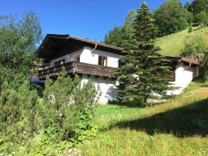 a white house with a wooden balcony on a hill at Ferienhaus Lengau in Saalbach-Hinterglemm