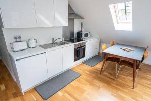 a kitchen with white cabinets and a wooden table at Plockton Distillery Flat in Plockton