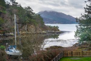 a boat sitting in the water next to a lake at Plockton Distillery Flat in Plockton
