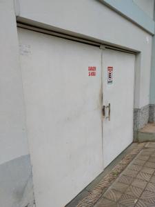 a white garage door with a no parking sign on it at Kitnet no Centro Garagem, ar e Wi-Fi in Itaperuna