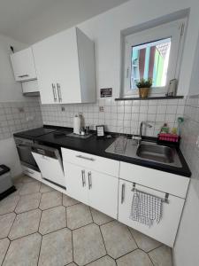 eine Küche mit weißen Schränken und einer Spüle in der Unterkunft Wolke13 - gemütliche 2 Zimmer Wohnung mit voll ausgestatteter Küche in der City von Menden in Menden + 22 Fotos