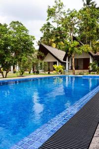 a blue swimming pool in front of a house at Pearl Villa Katunayake in Katunayaka