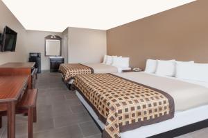 a hotel room with two beds and a desk at Deluxe Inn Denton in Denton