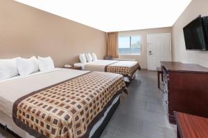 a hotel room with two beds and a flat screen tv at Deluxe Inn Denton in Denton