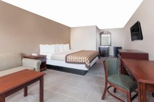 a hotel room with a bed and a table and chairs at Deluxe Inn Denton in Denton