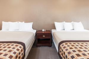 a hotel room with two beds and a night stand at Deluxe Inn Denton in Denton +6 photos