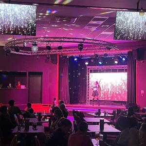 a woman standing on a stage in front of a crowd at Jasmine Corner - entertainment passes included - message for longer stays in Ringwood +25 photos