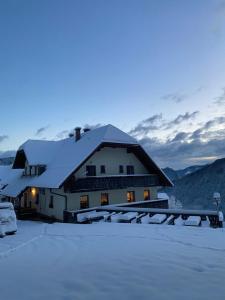 a house covered in snow in the mountains at Kmetija Matk in Solčava
