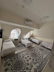 a bedroom with three beds and a rug at Mansarda hostel in Samarkand