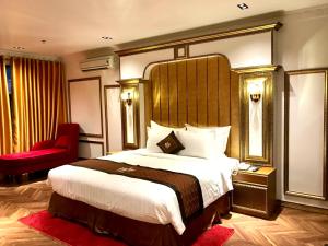 a hotel room with a large bed and a red chair at B.O.B HOTEL SIGNATURE in Cao Lãnh