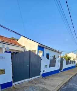 a white and blue house with a fence at Casa da Charrua in São Teotónio