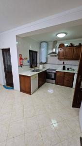 a large kitchen with wooden cabinets and a tile floor at Casa da Charrua in São Teotónio