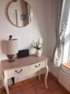 a table with a lamp and a mirror on a wall at Sonnys Rest in Ardara