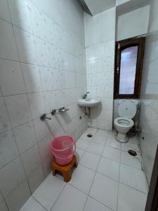 a bathroom with a toilet and a sink and a pink bucket at Hotel Taradavi Regency in Chhota Simla