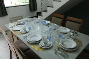 a table with glasses and plates and silverware on it at Casa Guarapari - Ferienhaus in Guarapari