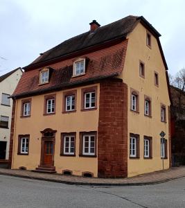 a yellow house with a brown roof on a street at Ferienwohnung am Kloster in Hornbach