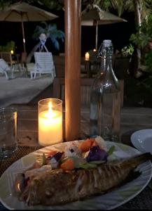 a plate of food on a table with a candle at Comfy Cool Breeze by eMzaz in Dhiffushi