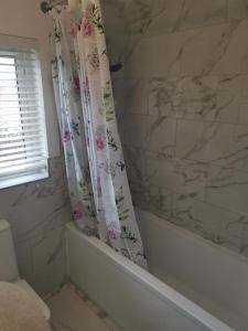 a bathroom with a marble shower curtain and a tub at Garden view Cosy Single Room in Derby