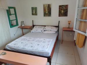 a small bedroom with a bed and two tables at Casa do Mato I in São Lourenço do Sul