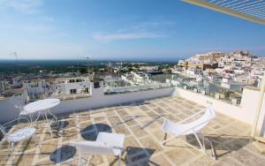 a balcony with white chairs and a view of a city at Suite Diffuse - Widespread Suite Collection PCB LUXURY in Ostuni