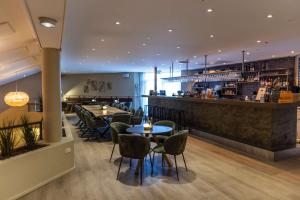 a restaurant with tables and chairs and a bar at Comwell Rebild Bakker in Skorping