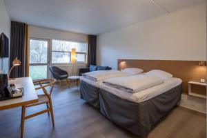 a hotel room with two beds and a desk and chair at Comwell Rebild Bakker in Skorping