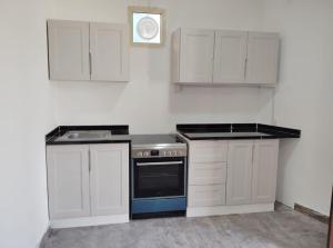 a kitchen with white cabinets and a stove top oven at Ebreez Heaven in Wāsiţ