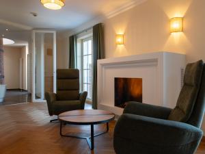 a living room with two chairs and a fireplace at Gutshotel Odelzhausen in Odelzhausen