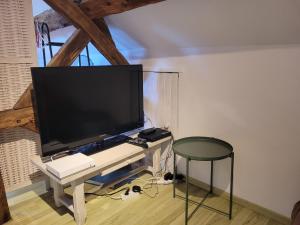 a flat screen tv on a white table with a stool at Gîte Le Four à Pain, 2 chambres, 2km du centre de Dole, in Dole