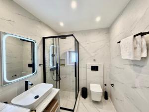 a white bathroom with a sink and a shower at Central Suites Aegina 5 in Egina +63 photos