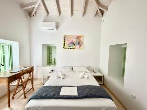 a white bedroom with a bed and a desk at Central Suites Aegina 5 in Egina