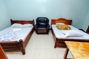 two beds and a chair in a room at Hulcity valley hotel in Kampala