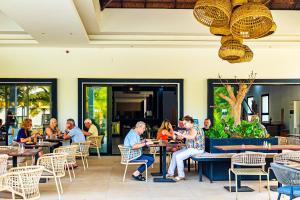 a group of people sitting at tables in a restaurant at Kalimba Beach Resort in Kotu