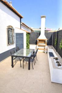 a patio with a table and chairs and a fireplace at Casa luz e conforto-Casa 20 in Almancil