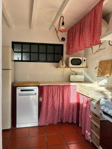 a kitchen with red curtains and a white dishwasher at Pisco Charming House - Alter Pedroso in Alter do Chão