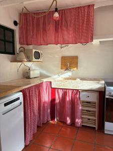 a kitchen with a sink and a counter with red curtains at Pisco Charming House - Alter Pedroso in Alter do Chão +27 photos