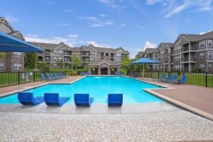 a swimming pool with blue chairs and apartments at Landing Spectacular 1BD Pool Courtyard in Broken Arrow