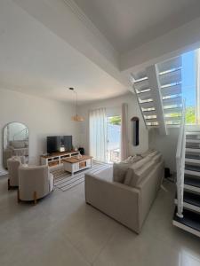 a living room with a couch and chairs and a tv at Casa beira Mar in Itanhaém