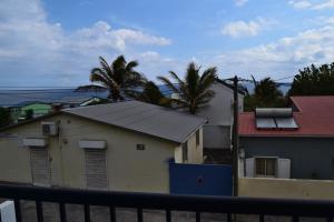 a building with a black roof with palm trees in the background at Corail Azur Terre Sainte in Saint-Pierre